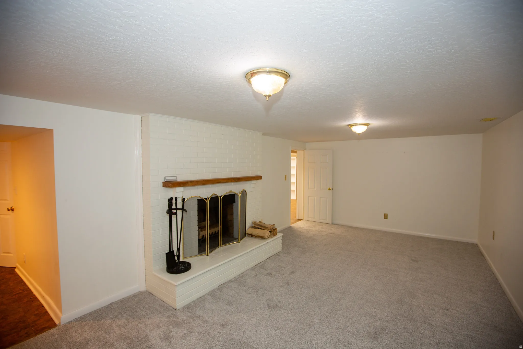 White brick fireplace with a wood mantle and brass fire screen