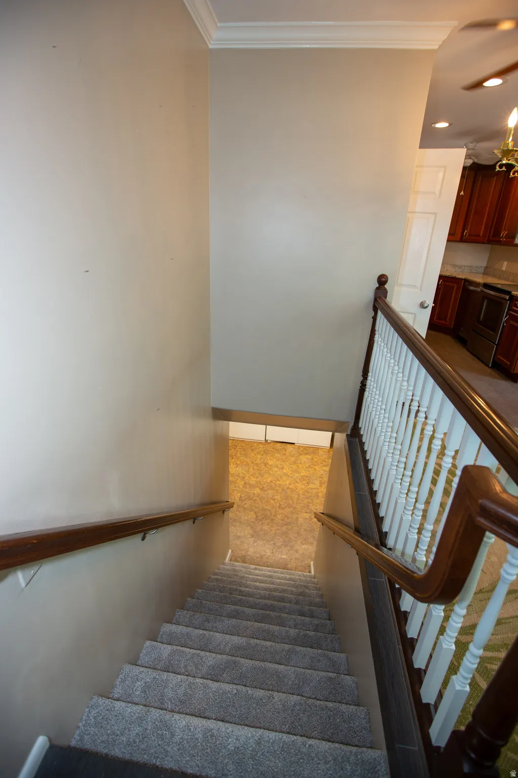 Carpeted staircase with dark wood handrails and white balusters