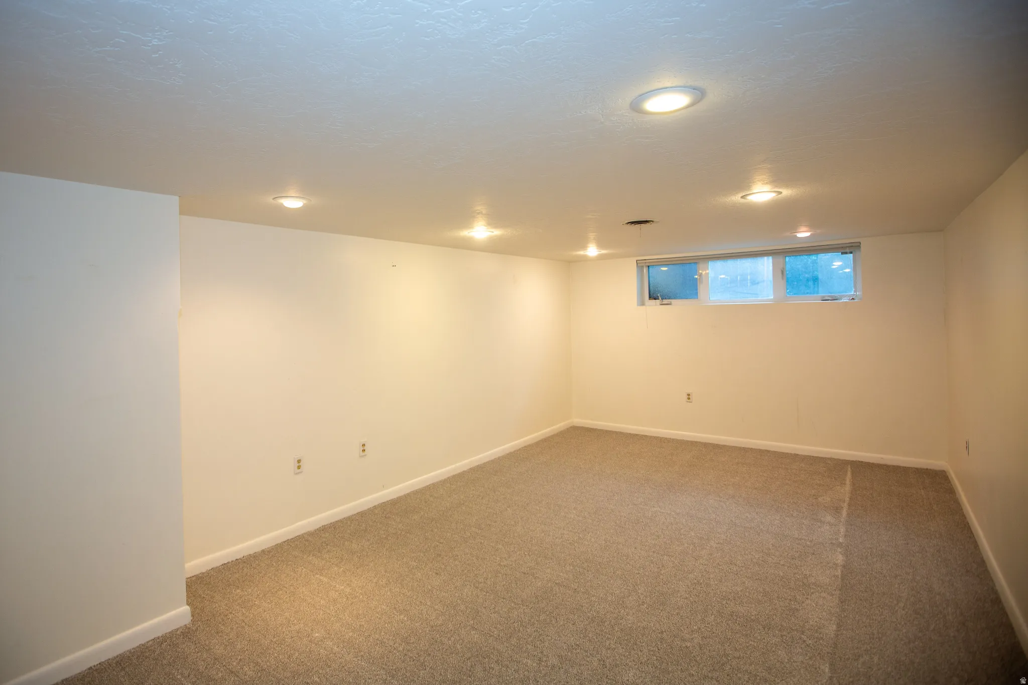 Carpeted room featuring recessed lighting, white walls, and a multi-pane window