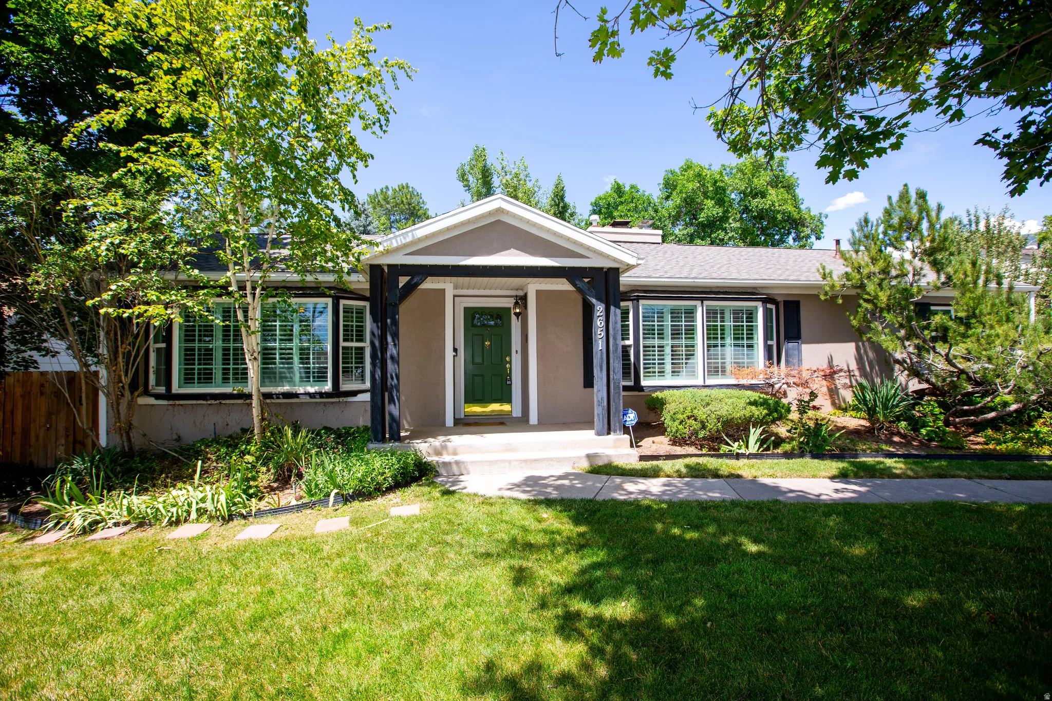 Contemporary exterior with a covered entry, dark green front door, and white shuttered windows