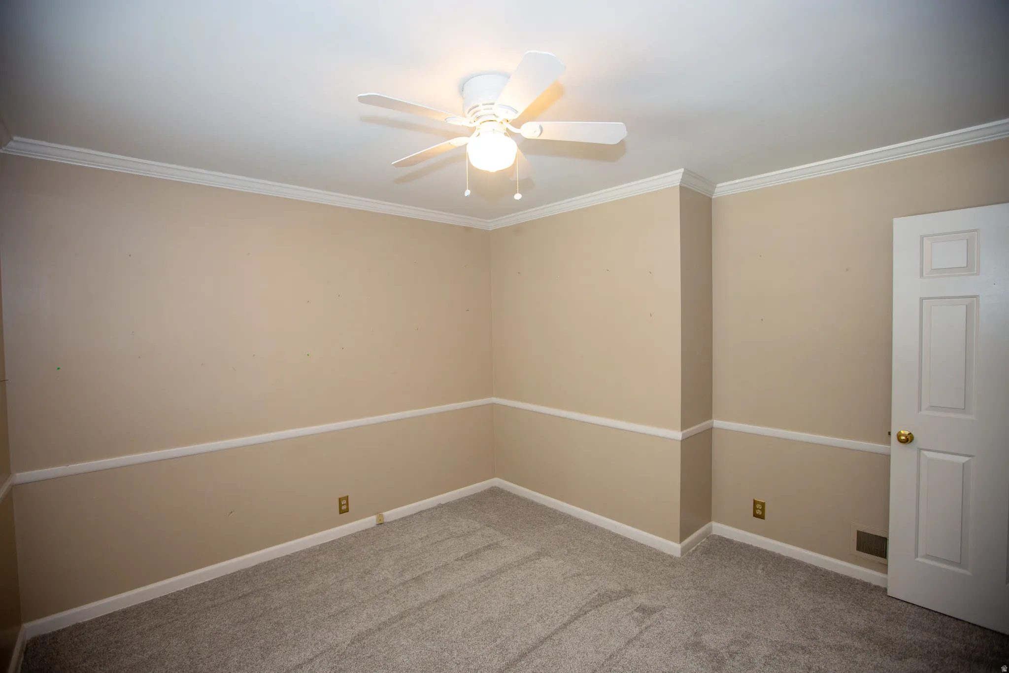 Interior room featuring neutral-toned walls with chair rail molding and crown molding