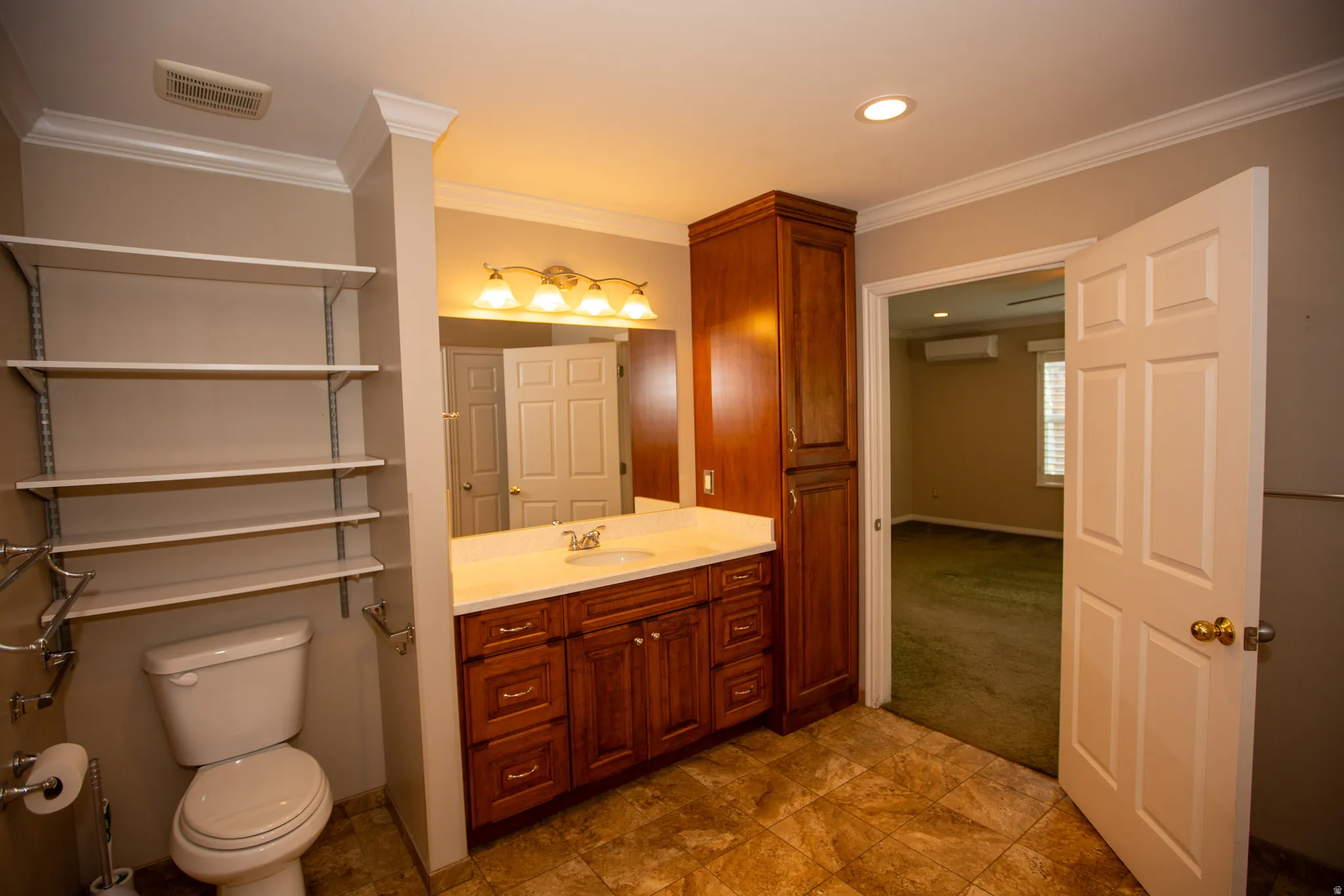 Bathroom featuring a single vanity with wood cabinetry, a light-toned countertop, and a wall-mounted mirror with sconce lighting