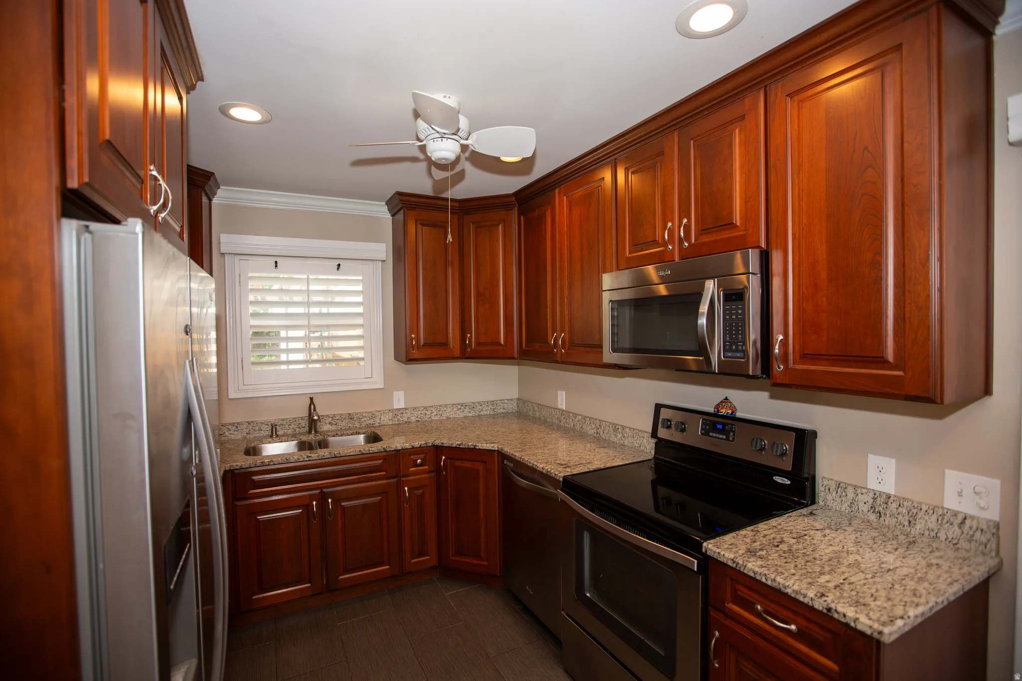 Kitchen featuring rich wood cabinetry, granite countertops, stainless steel appliances, recessed lighting, and wood-finish flooring