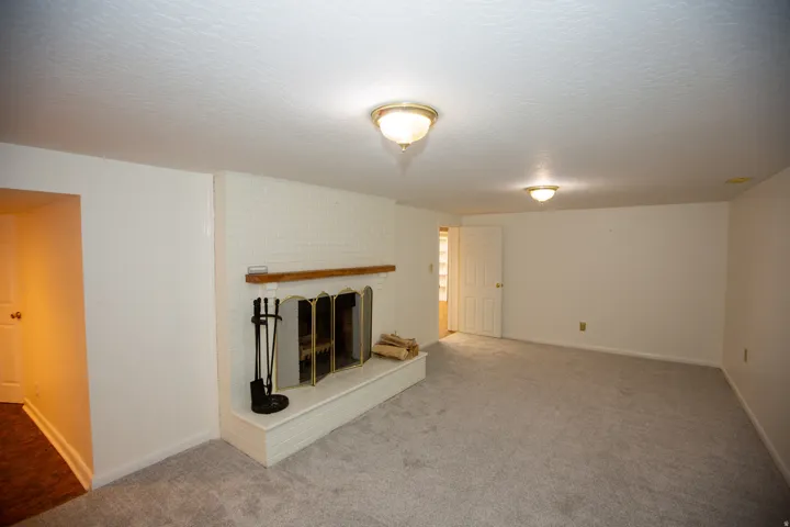 White brick fireplace with a wood mantle and brass fire screen