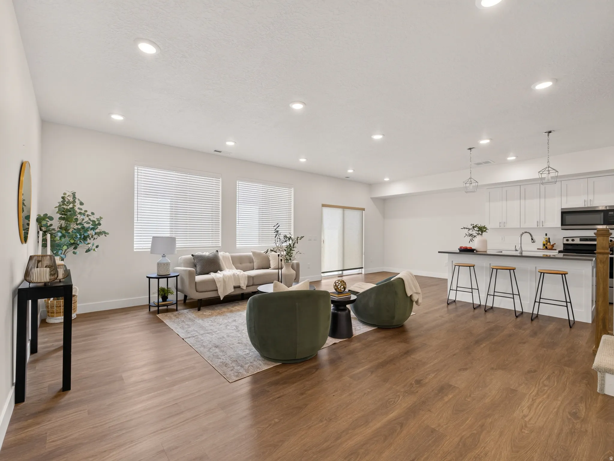 Open-concept living space featuring wood-finish flooring, recessed lighting, and a kitchen island with seating
