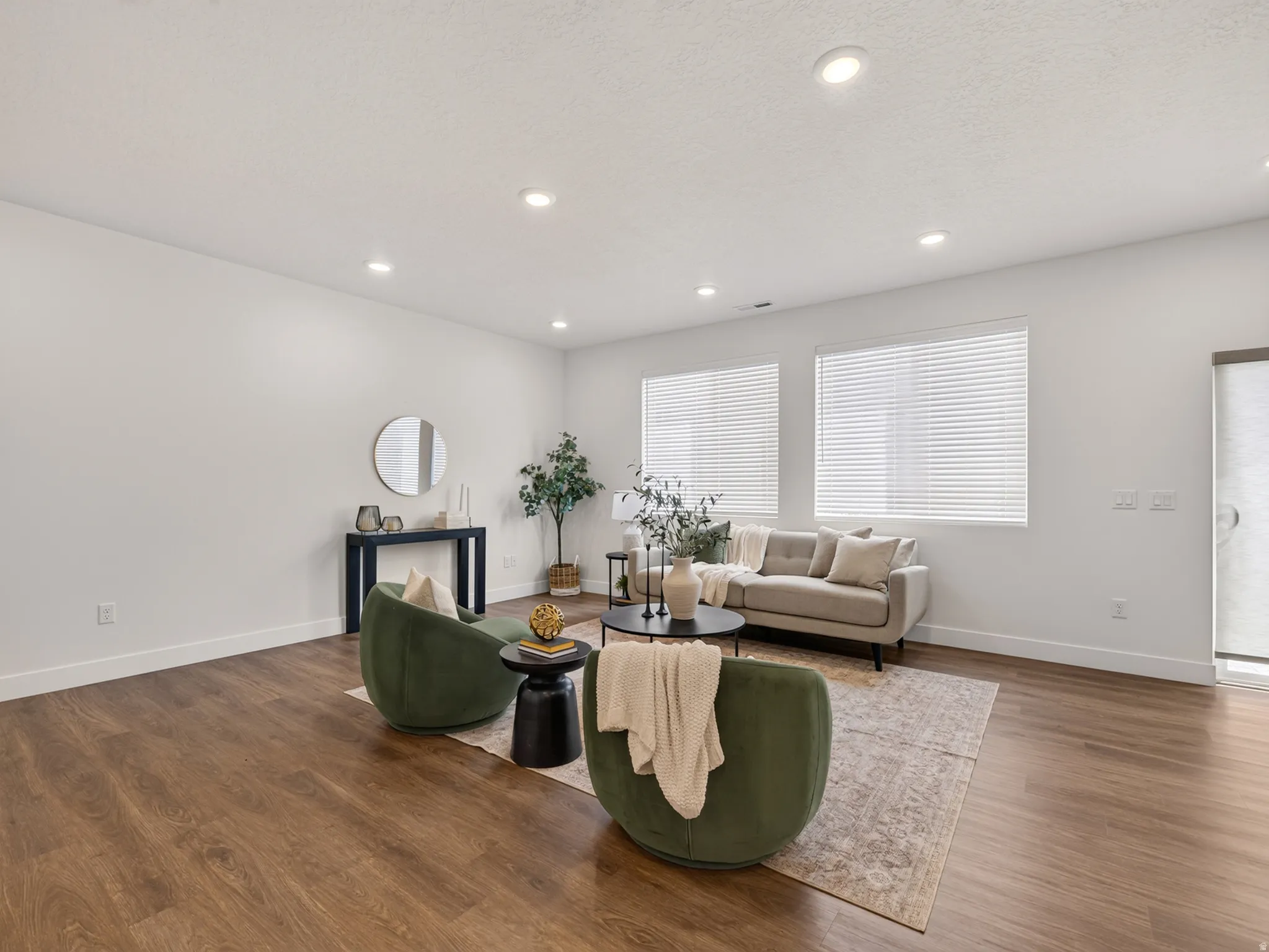 Spacious living area featuring wood-finish flooring, recessed lighting, and white baseboards