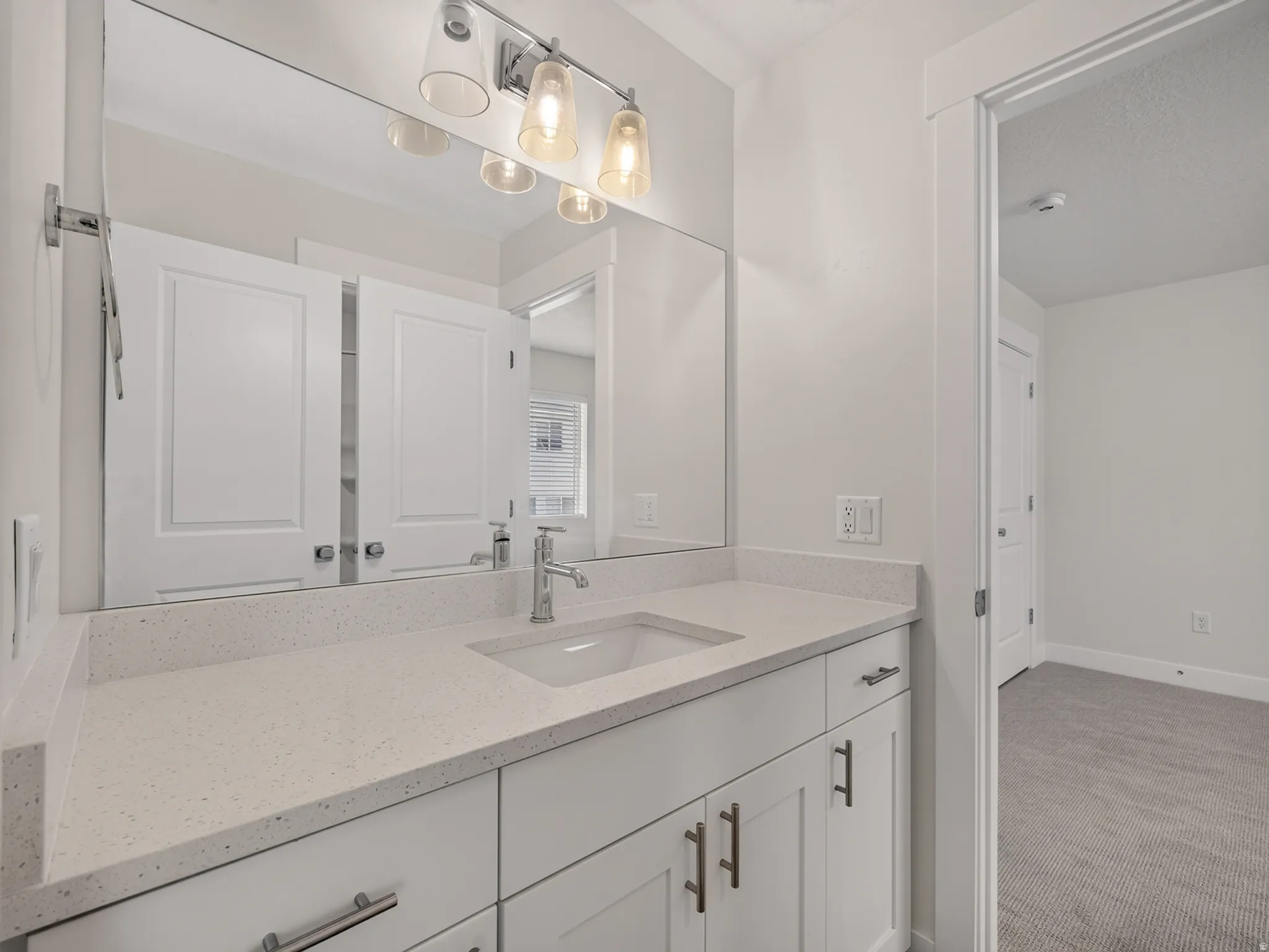 Vanity area featuring an integrated sink, polished chrome faucet, and quartz-finish countertop