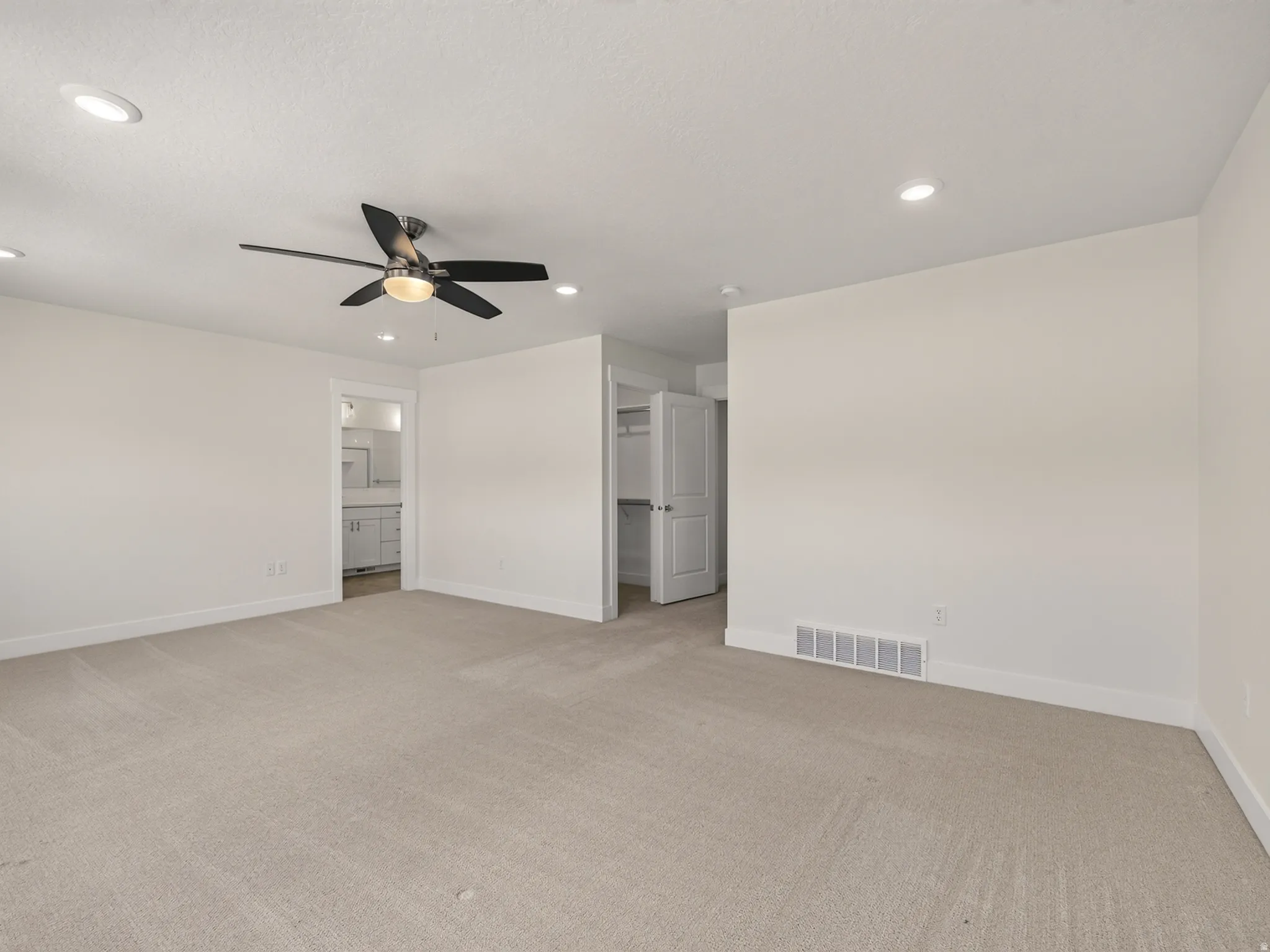 Spacious room featuring neutral carpeting, recessed ceiling lighting, a contemporary ceiling fan, and white baseboards