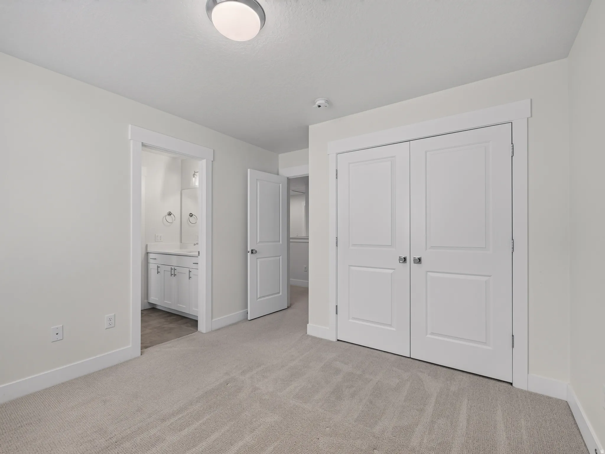 Carpeted room featuring a double-door closet, a white trim package, and a flush-mount ceiling light