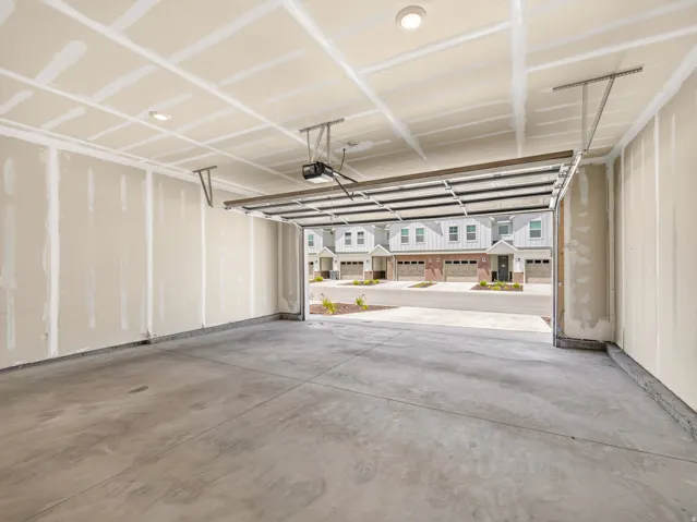 Spacious garage featuring a concrete floor, exposed drywall walls, recessed ceiling lighting, and an overhead garage door opener