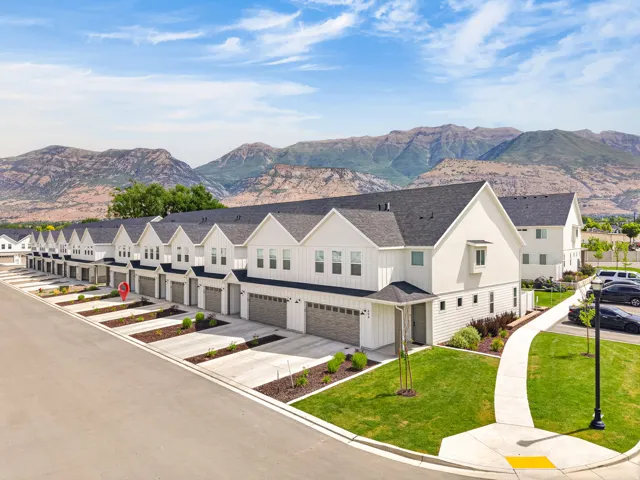 Modern townhome community featuring a consistent architectural style with white siding, dark roofs, and attached garages