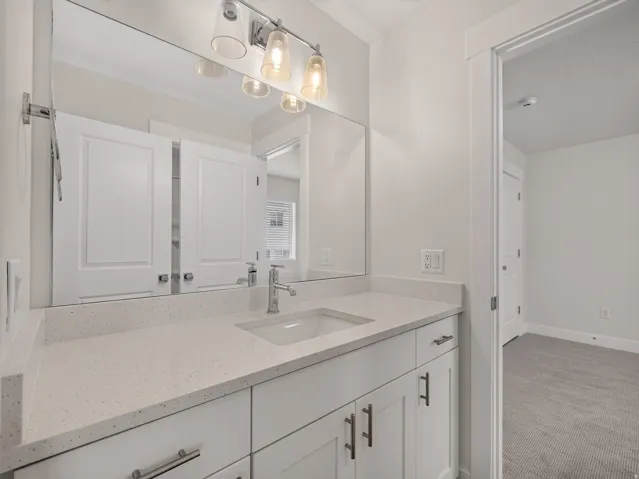 Vanity area featuring an integrated sink, polished chrome faucet, and quartz-finish countertop
