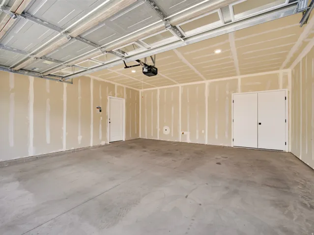 Spacious garage featuring a concrete floor, exposed drywall, recessed lighting, and an automatic garage door opener