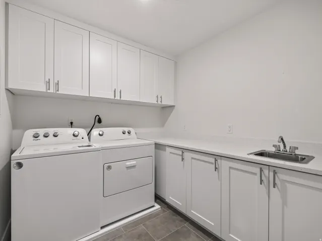 Utility room featuring white shaker-style cabinetry with brushed nickel hardware, light-toned countertops, and a stainless steel sink with a chrome faucet
