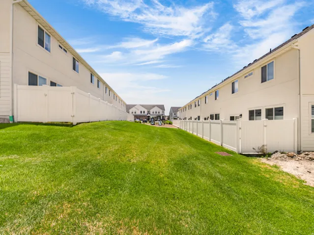 Expansive grassy area bordered by white vinyl fencing