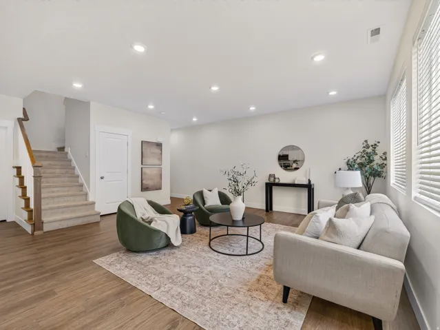 Open living area featuring wood-finish flooring, recessed lighting, and bright white walls