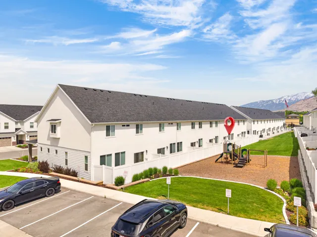 Townhome community featuring white exteriors, dark shingle roofs, and a children's play area with wood chip ground cover