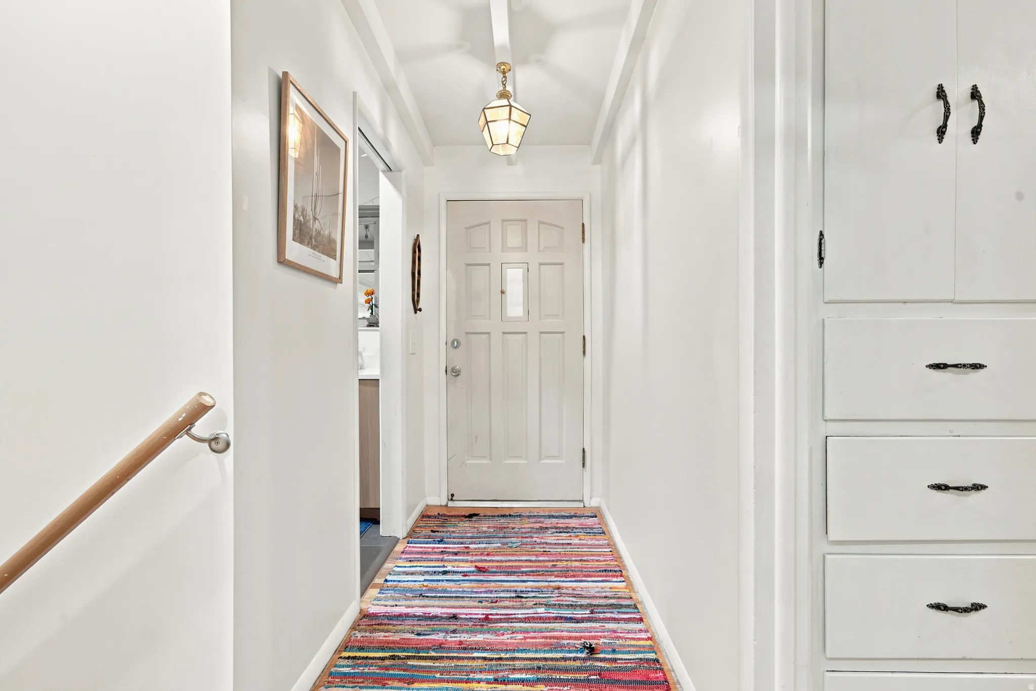 Entryway featuring a paneled door, built-in cabinetry, exposed beam ceiling, and a decorative ceiling light fixture