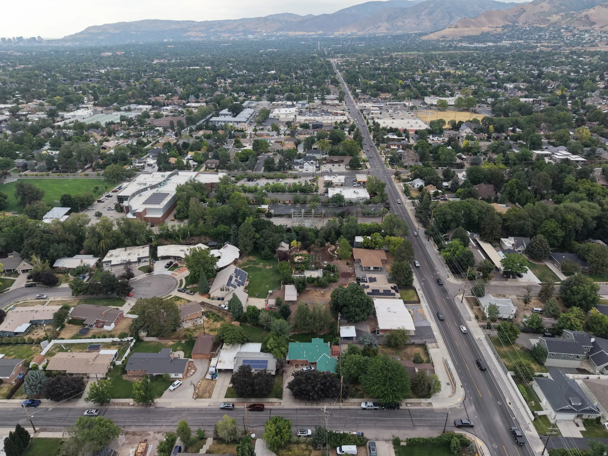 Residential neighborhood with mature trees, established properties, and distant mountain ranges