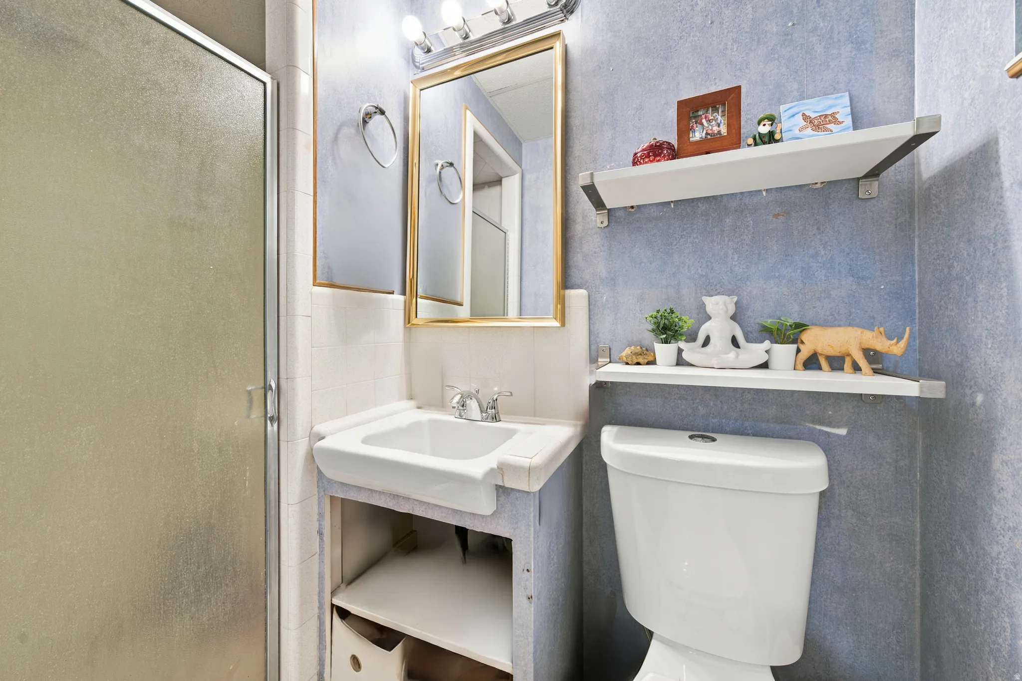 Bathroom featuring a built-in white vanity sink, a gold-framed wall mirror, and a chrome light fixture