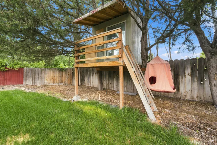 Backyard featuring a custom-built treehouse with an elevated deck, wood railing, and a window
