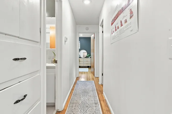 Hallway featuring built-in white cabinetry, hardwood flooring, and recessed lighting