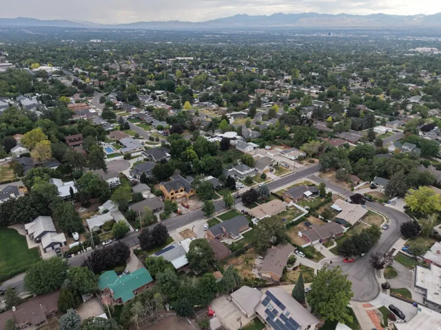 Aerial perspective showcasing a residential neighborhood with numerous single-family homes, mature tree canopy, and curving streets