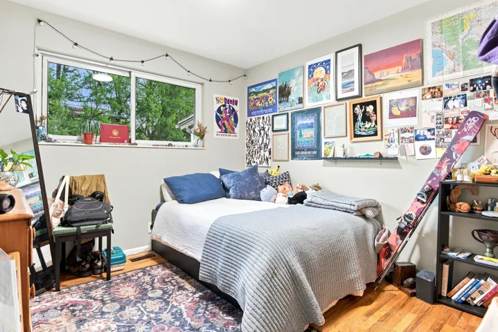 Bedroom featuring light gray walls, wood-finish flooring, and a large window providing ample natural light