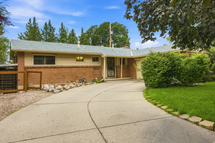 Ranch-style residence featuring a brick and siding exterior, a light-colored shingle roof, and a curved concrete driveway