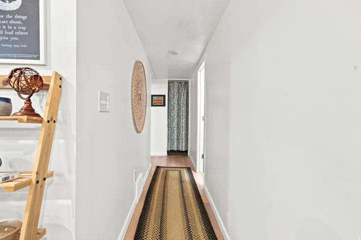 Hallway featuring light wood-finish flooring, recessed ceiling lighting, and a white interior door