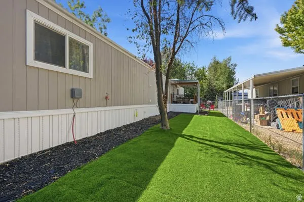 Manicured artificial turf lawn alongside a light brown siding exterior with white trim and white skirting
