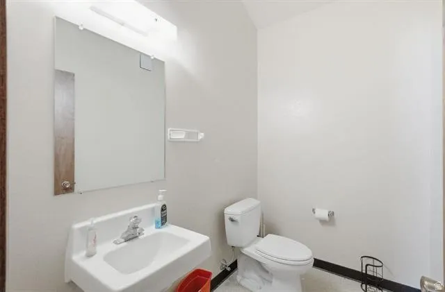 White wall-mounted sink with chrome faucet, large wall mirror, and overhead vanity lighting