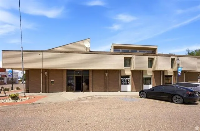 Commercial building featuring brick and horizontal siding, multiple glass entryways, and upper-level windows