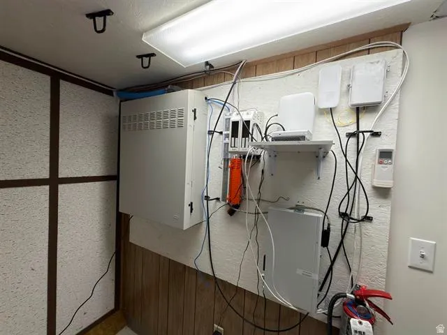 Utility area featuring wall-mounted equipment and an overhead fluorescent light fixture