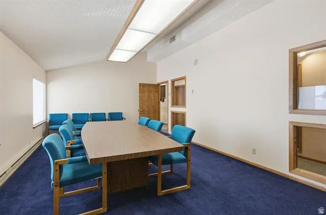 Spacious room featuring a vaulted ceiling and rich blue carpeting