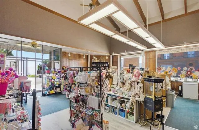 Expansive retail space featuring large storefront windows, wood-paneled walls, and a dropped ceiling with exposed wooden beams