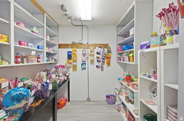 Storage room featuring extensive built-in shelving, track lighting, and wood-finish flooring