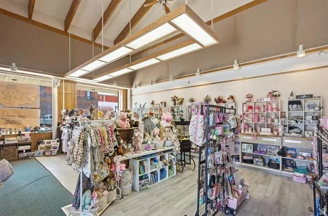 Commercial interior featuring vaulted ceilings with exposed wood beams, recessed lighting, and large storefront windows
