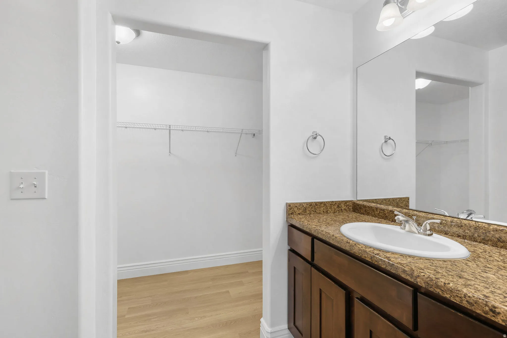 Bathroom vanity with a polished stone countertop, integrated sink, and dark wood cabinetry