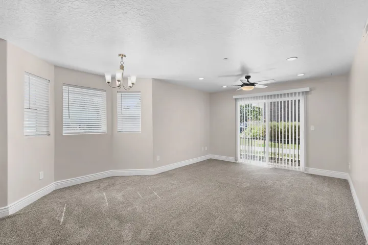 Spacious room featuring neutral paint, gray carpet, multiple windows with blinds, a ceiling fan, and recessed lighting