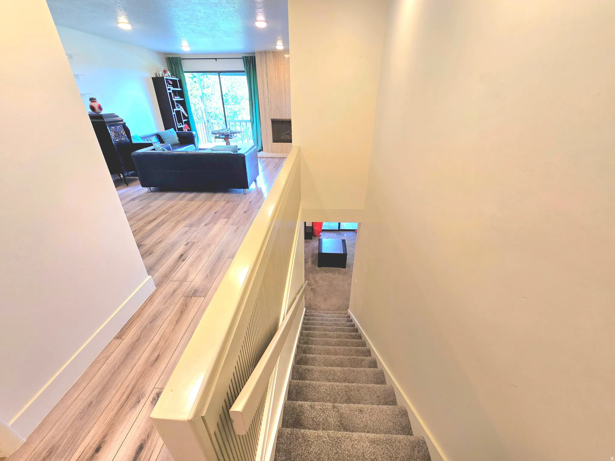 Upper level living space featuring wood-finish flooring, recessed lighting, and a fireplace with a stone surround