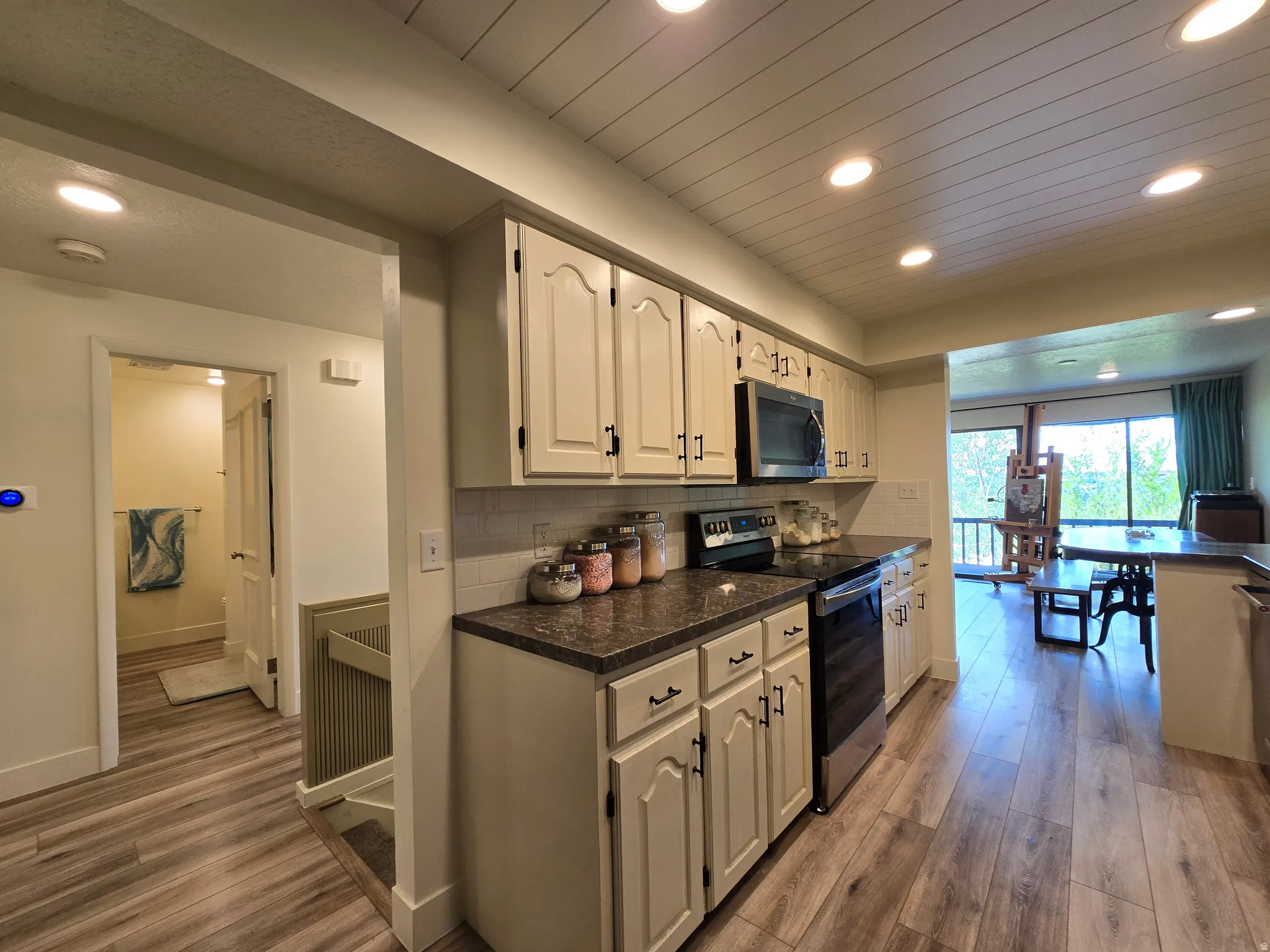 Functional kitchen featuring cream cabinetry with dark hardware, a subway tile backsplash, and dark countertops