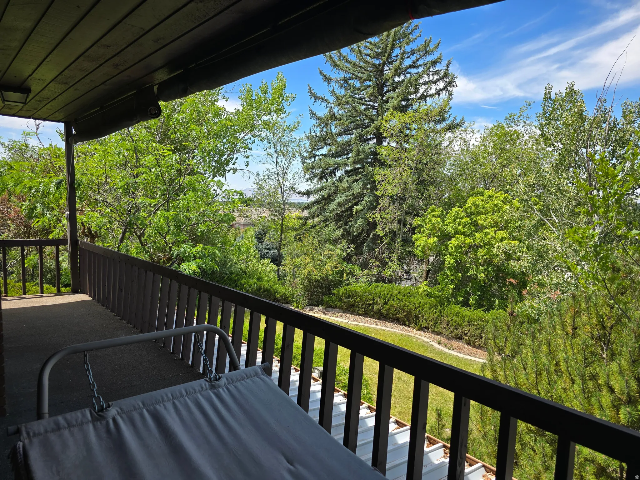Covered outdoor deck with dark wood-finish ceiling, dark wood-finish railings, and a dark floor surface
