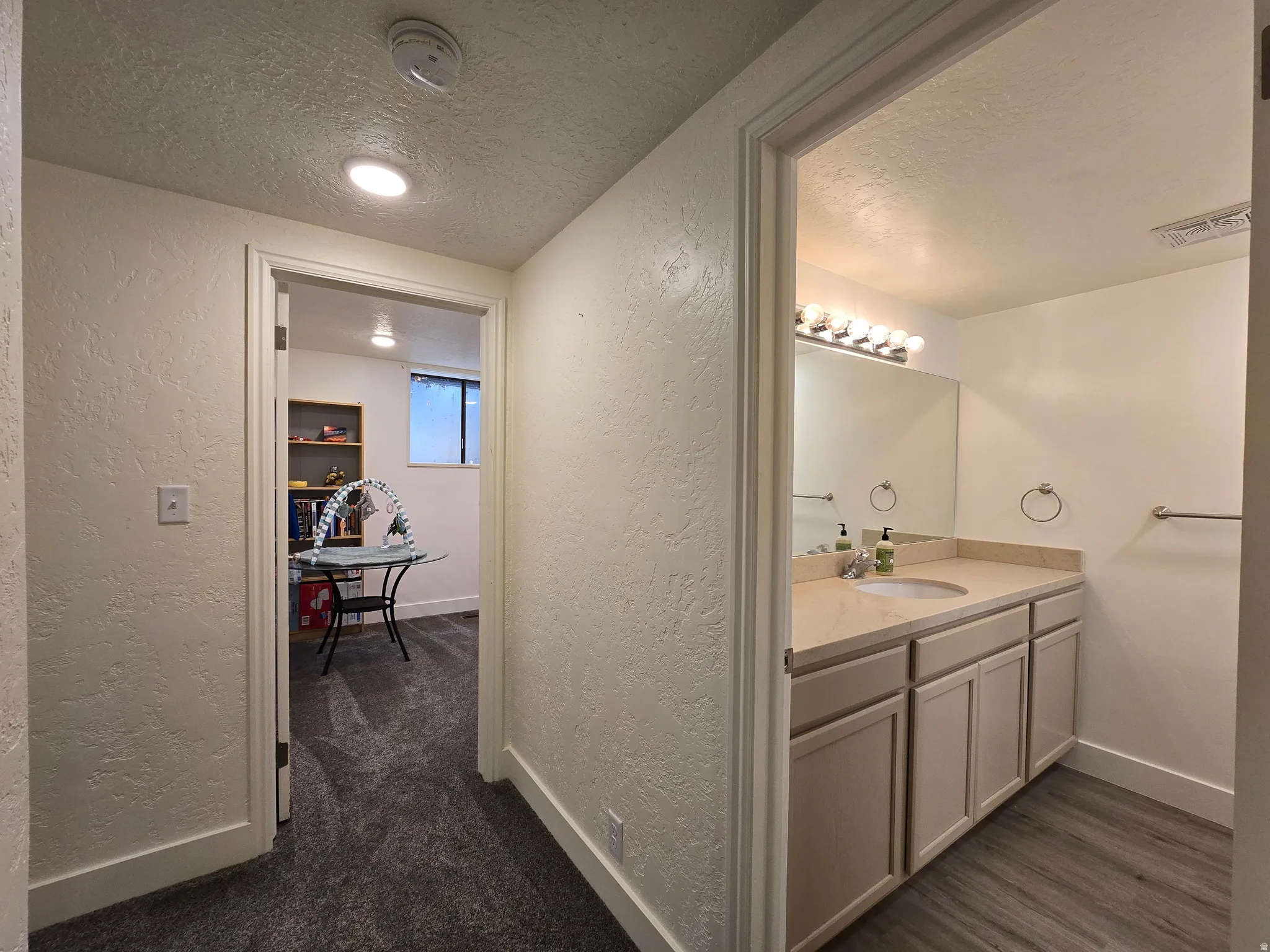 Bathroom featuring a single vanity with light-toned cabinetry, a built-in sink, and a large wall-mounted mirror