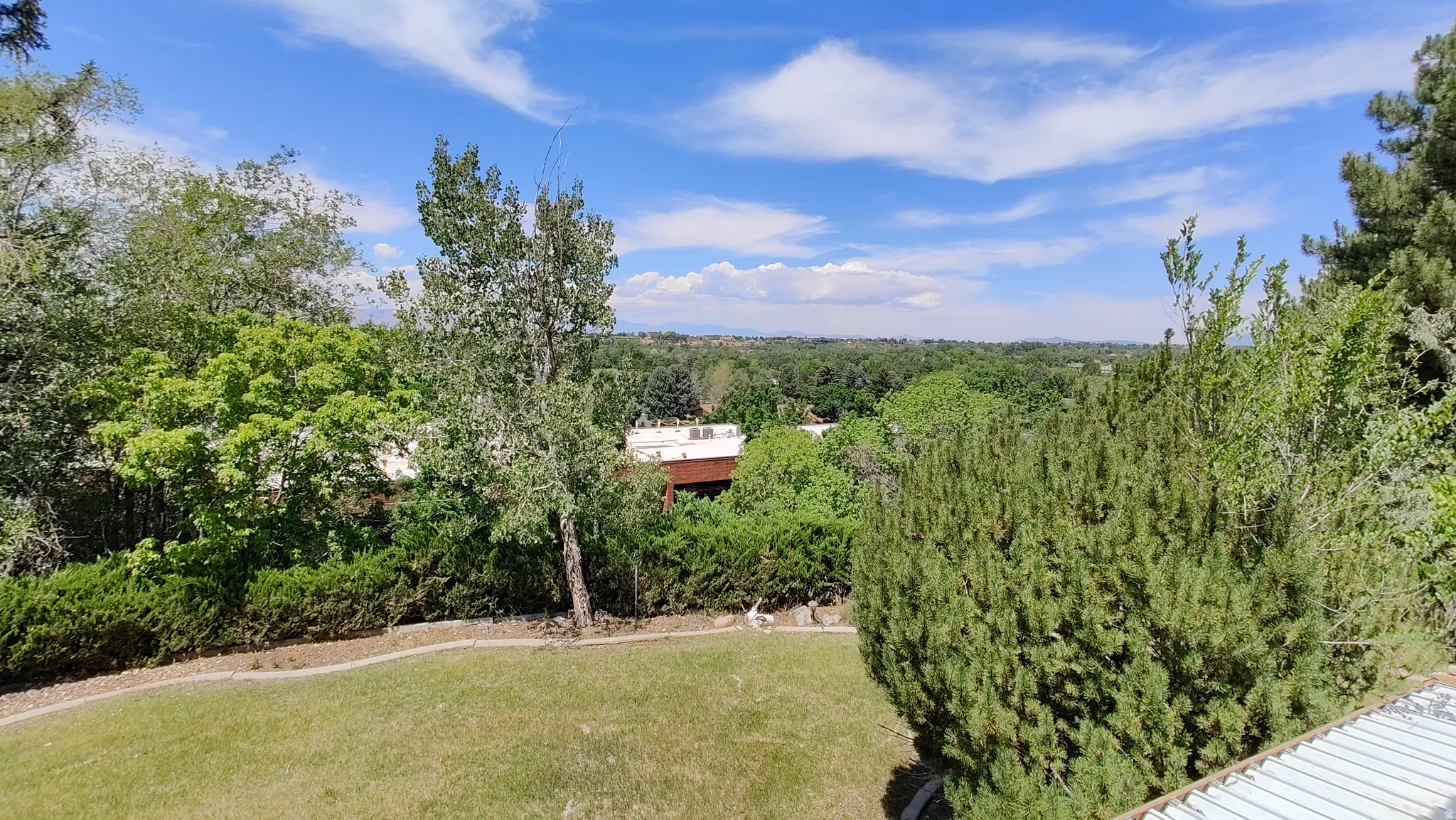 Expansive outdoor space featuring a manicured lawn, mature trees, and established shrubbery