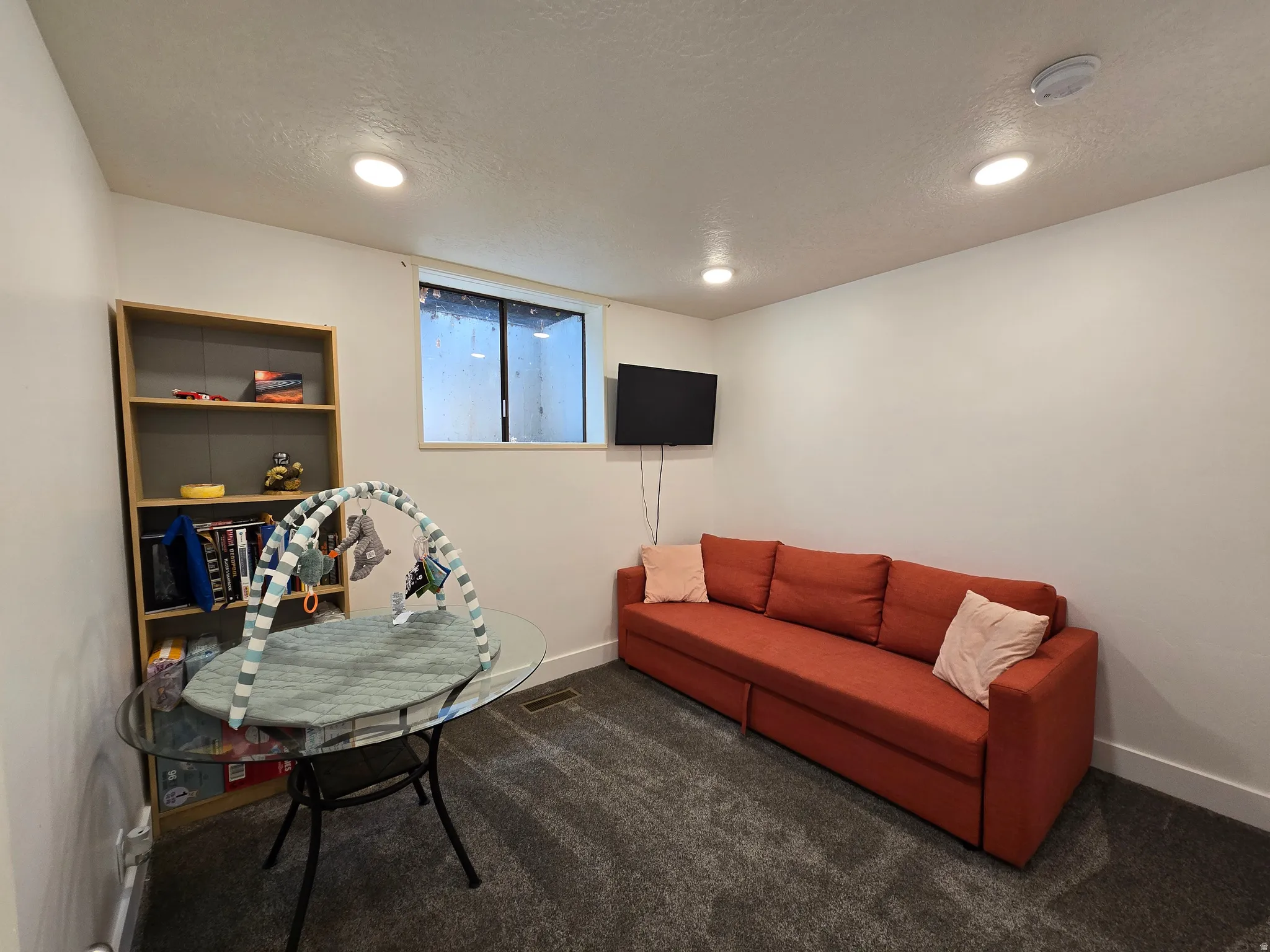 Spacious room featuring neutral white walls, dark gray carpeting, and recessed ceiling lighting