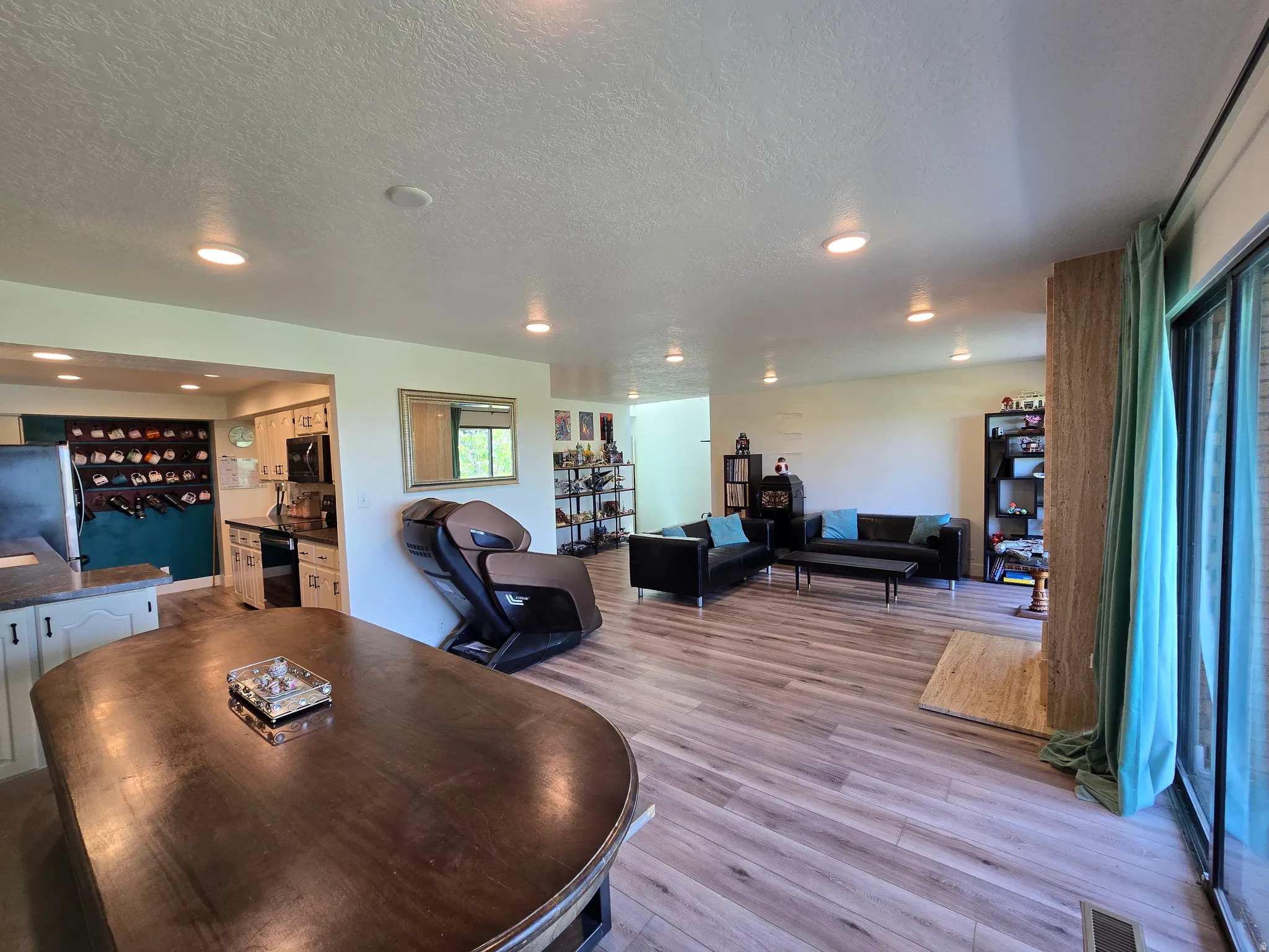 Open-concept living space featuring wood-finish flooring, recessed lighting, and a kitchen with white cabinetry and dark countertops