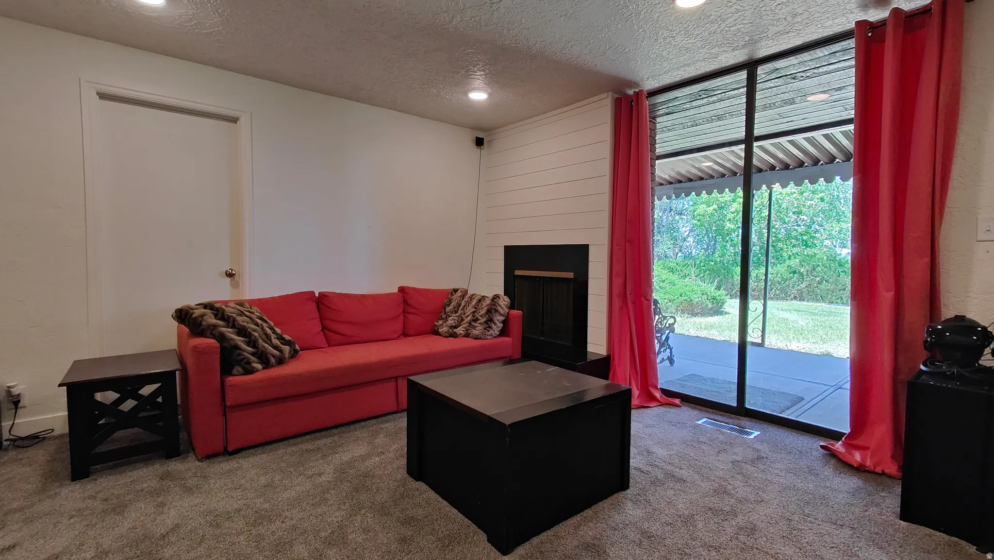 Living space featuring recessed lighting, a fireplace with a black surround, and white shiplap detailing