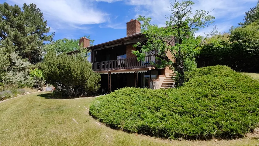 Terraced property with brick construction featuring multiple chimneys and a substantial upper-level balcony