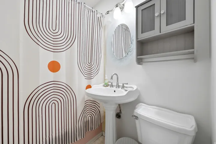 Pedestal sink with chrome faucet, wall-mounted storage cabinet, and white toilet